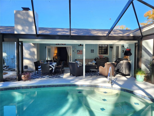 view of swimming pool featuring outdoor lounge area, ceiling fan, a patio, and glass enclosure