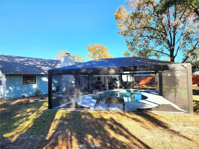 rear view of house with a lanai, a chimney, a yard, an outdoor pool, and a patio
