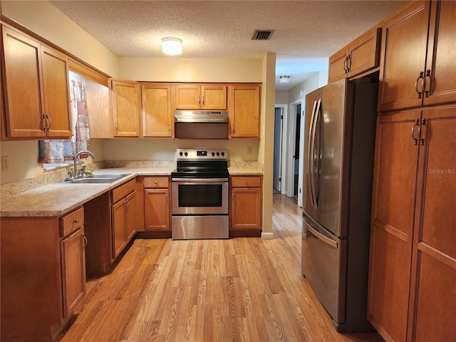 kitchen featuring a textured ceiling, stainless steel appliances, light hardwood / wood-style flooring, and sink