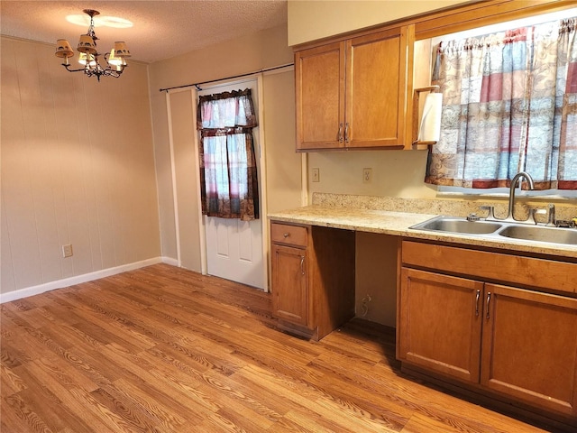 kitchen featuring light hardwood / wood-style floors, sink, hanging light fixtures, and a notable chandelier