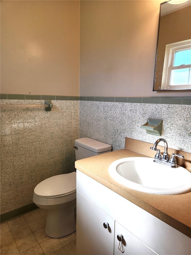 bathroom featuring toilet, vanity, tile patterned floors, and tile walls