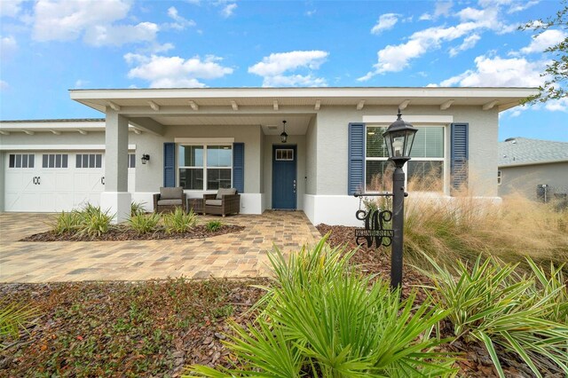 10564 SW 98th Ln, Ocala, FL 34481 - view of front of property with stucco siding, a garage, an outdoor hangout area, and driveway