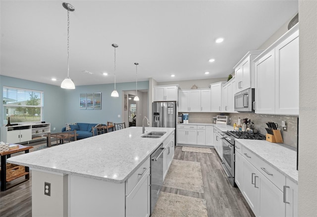 kitchen featuring pendant lighting, white cabinetry, stainless steel appliances, and a kitchen island with sink