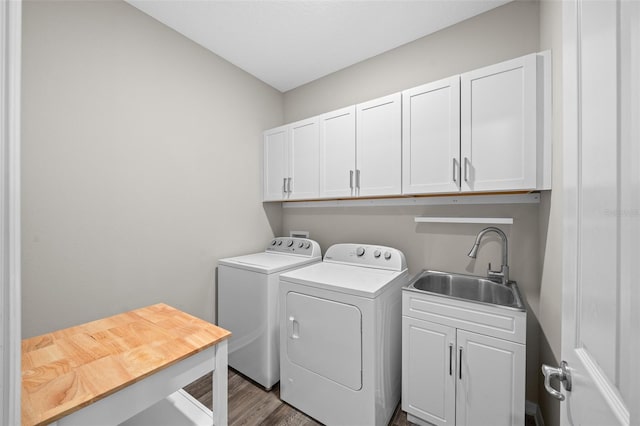 laundry room with washing machine and dryer, sink, cabinets, and wood-type flooring