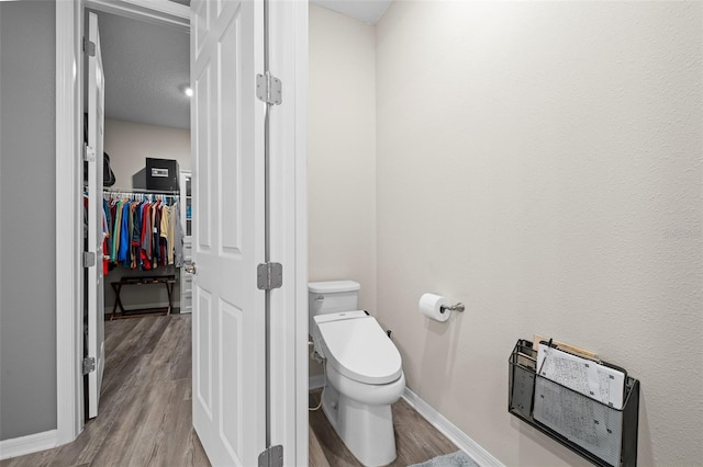 bathroom featuring a textured ceiling, hardwood / wood-style flooring, and toilet