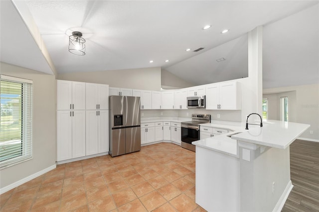 kitchen featuring sink, stainless steel appliances, white cabinets, vaulted ceiling, and kitchen peninsula