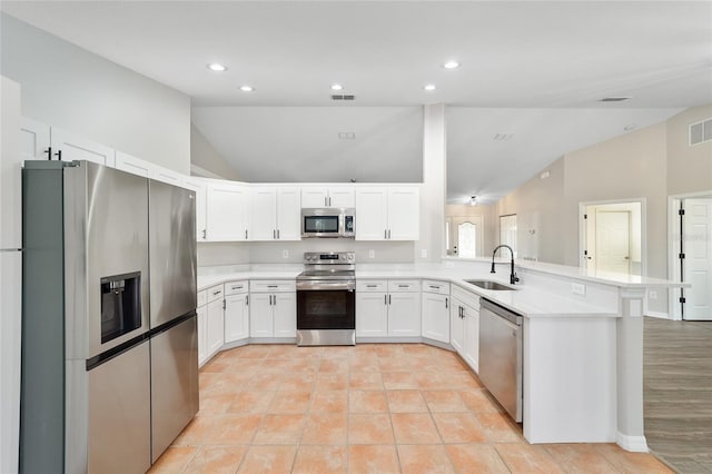 kitchen featuring lofted ceiling, sink, light tile patterned floors, appliances with stainless steel finishes, and white cabinets