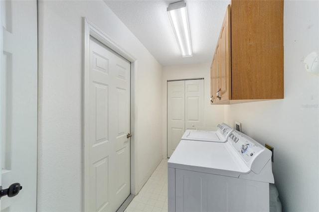 clothes washing area with cabinets and washing machine and clothes dryer