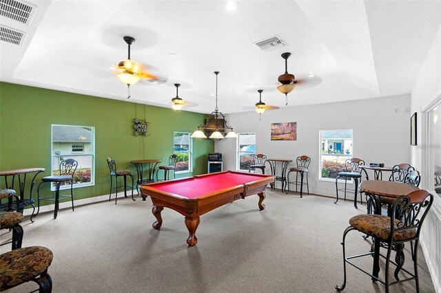 rec room featuring a raised ceiling, light colored carpet, and ceiling fan