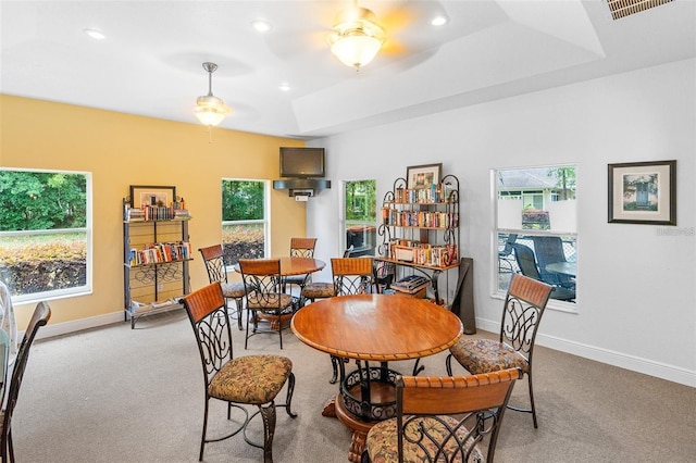 carpeted dining area featuring ceiling fan and a raised ceiling