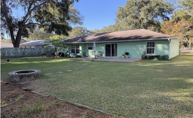 rear view of property with a fire pit, a yard, and a patio