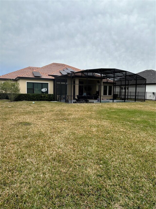 back of house with a yard and glass enclosure