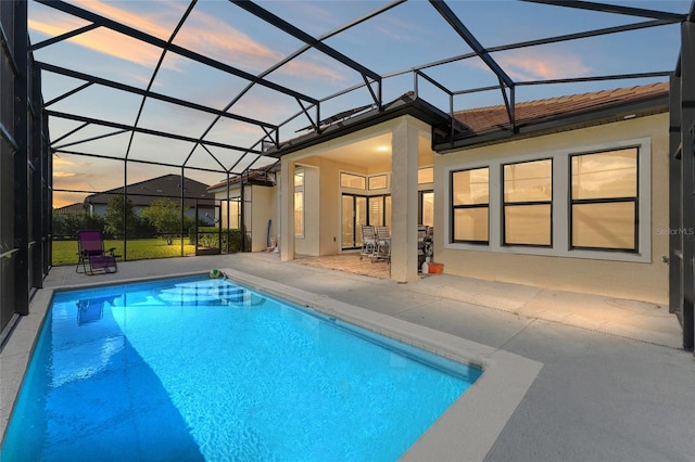 pool at dusk featuring a patio and glass enclosure