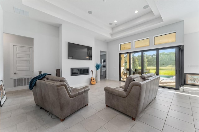 tiled living room featuring a raised ceiling and a high ceiling