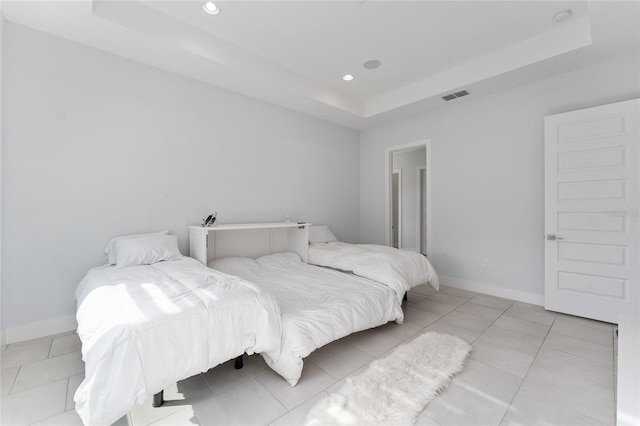 bedroom with a tray ceiling and light tile patterned floors