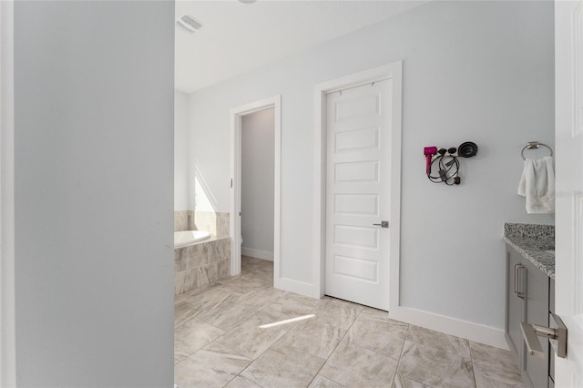 bathroom with vanity and tiled bath