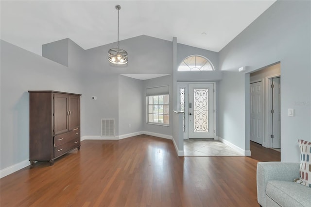 foyer featuring high vaulted ceiling, hardwood / wood-style floors, and an inviting chandelier