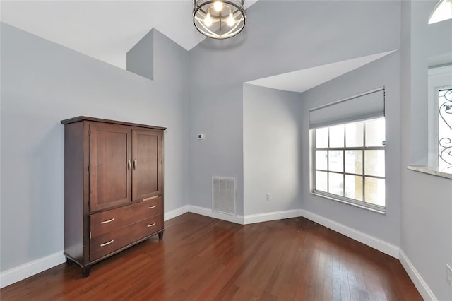 unfurnished bedroom with dark hardwood / wood-style flooring and a high ceiling