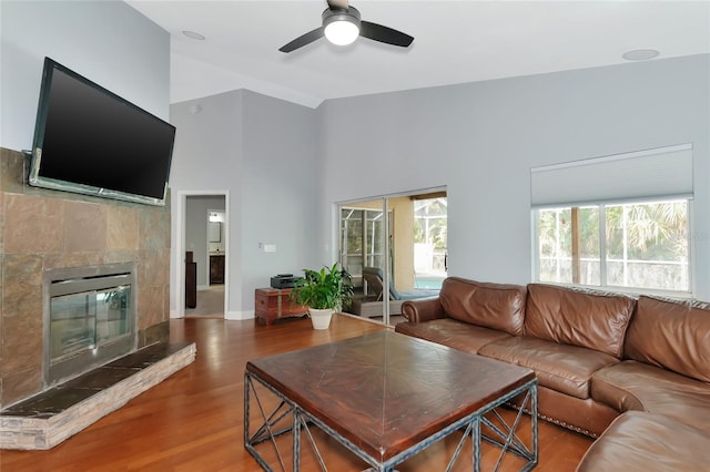 living room featuring hardwood / wood-style floors, a tile fireplace, and ceiling fan