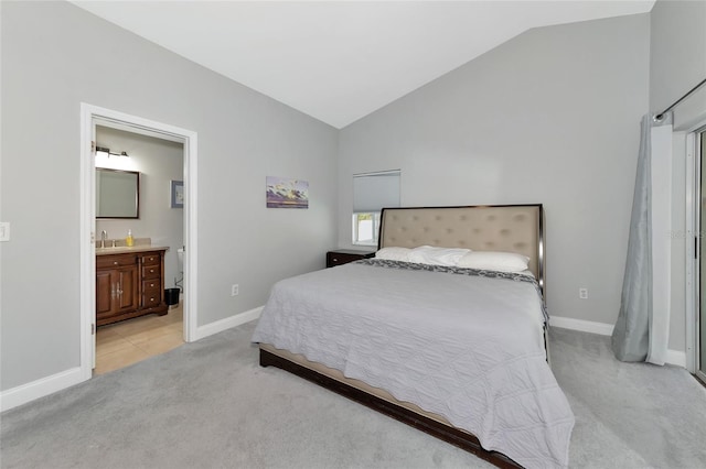 bedroom with lofted ceiling, connected bathroom, and light carpet