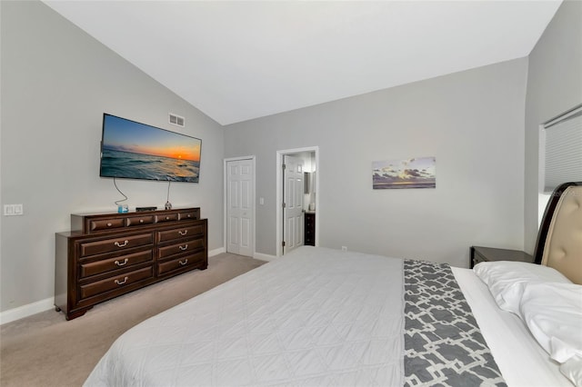 carpeted bedroom featuring ensuite bath, vaulted ceiling, and a closet