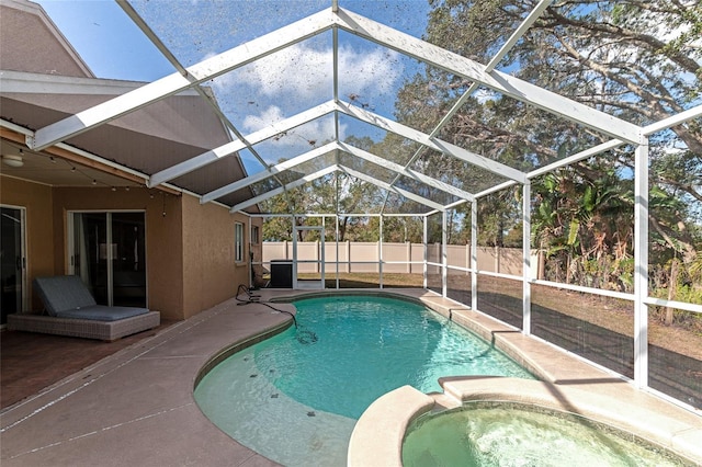 view of swimming pool with a patio, glass enclosure, and an in ground hot tub