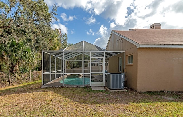 back of property featuring a fenced in pool, a lawn, central air condition unit, and glass enclosure