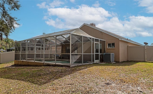 rear view of house featuring a yard, a swimming pool, glass enclosure, and central air condition unit