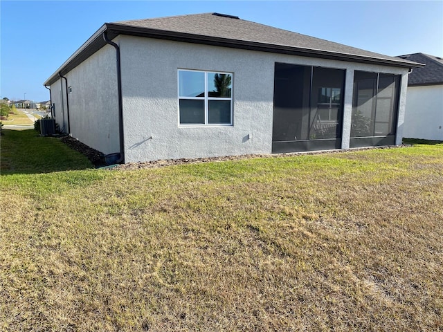 rear view of house with a lawn, central air condition unit, and a sunroom