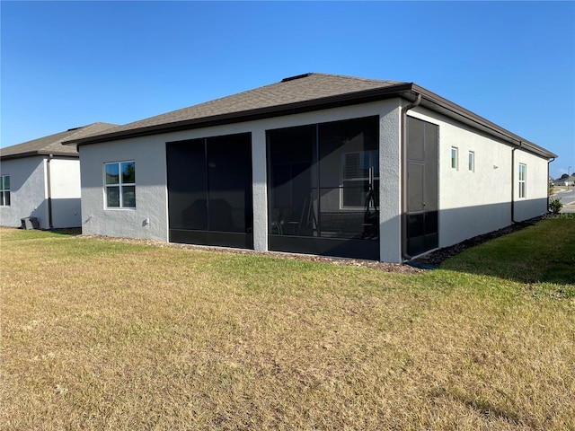 back of property featuring a sunroom and a lawn