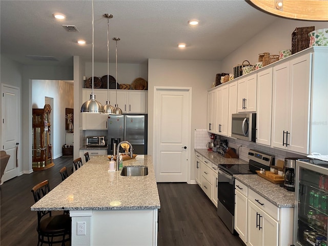 kitchen featuring sink, an island with sink, pendant lighting, a breakfast bar area, and appliances with stainless steel finishes