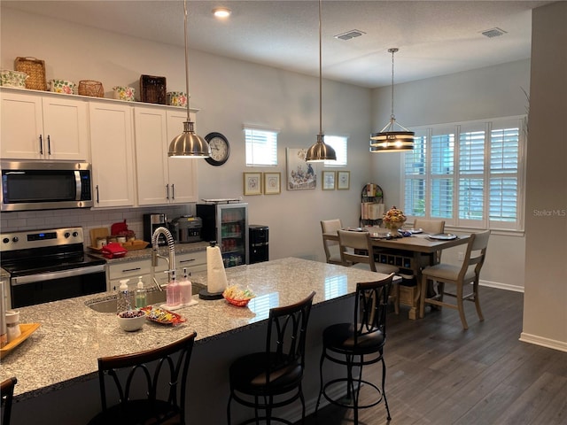 kitchen with white cabinetry, sink, stainless steel appliances, dark hardwood / wood-style flooring, and pendant lighting