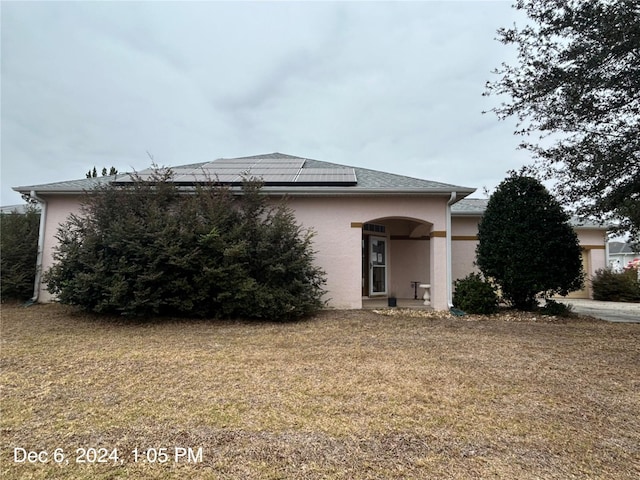 view of front of house with a front yard and solar panels