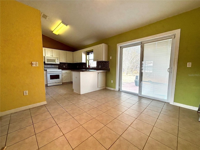 kitchen featuring white cabinets, lofted ceiling, white appliances, and light tile patterned floors