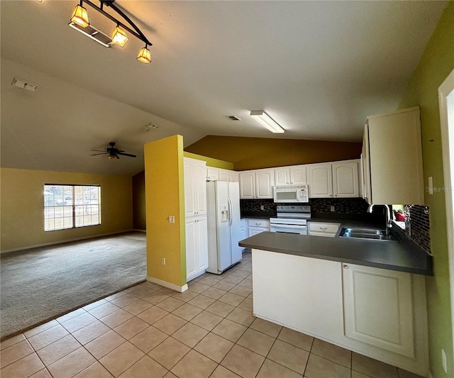 kitchen with kitchen peninsula, white appliances, sink, light tile patterned floors, and lofted ceiling