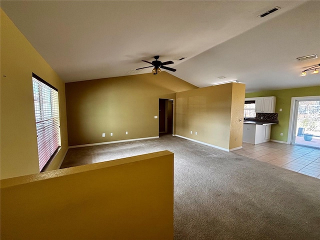 unfurnished living room with ceiling fan, light colored carpet, and vaulted ceiling