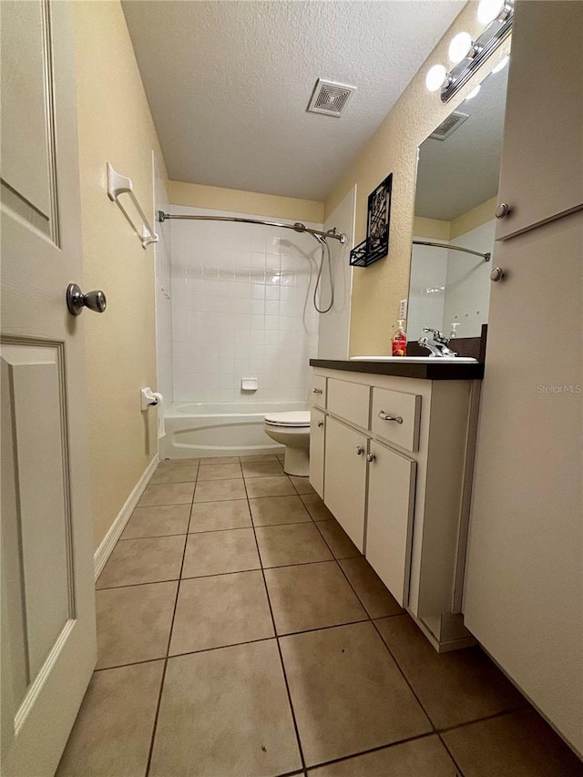 full bathroom with vanity, tile patterned floors, tiled shower / bath combo, toilet, and a textured ceiling