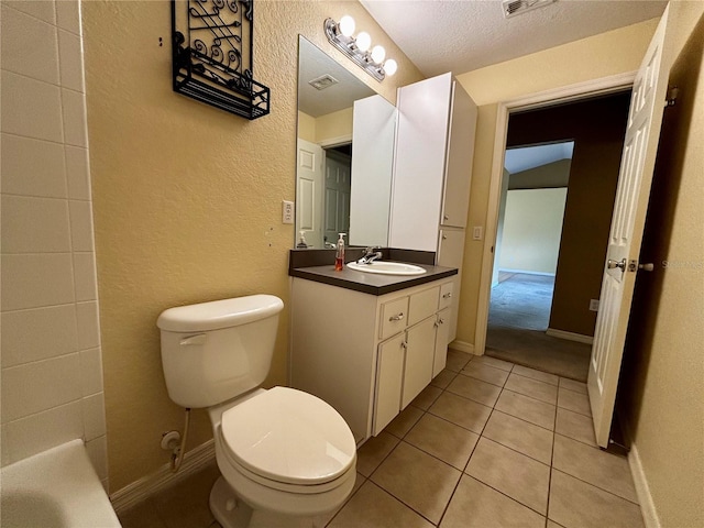 bathroom with tile patterned floors, vanity, a textured ceiling, and toilet