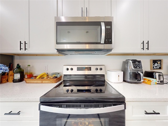 kitchen featuring light stone counters, white cabinetry, and stainless steel appliances