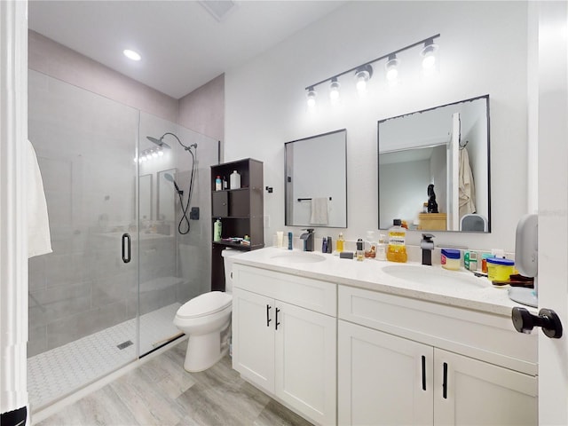 bathroom featuring hardwood / wood-style floors, vanity, toilet, and a shower with door