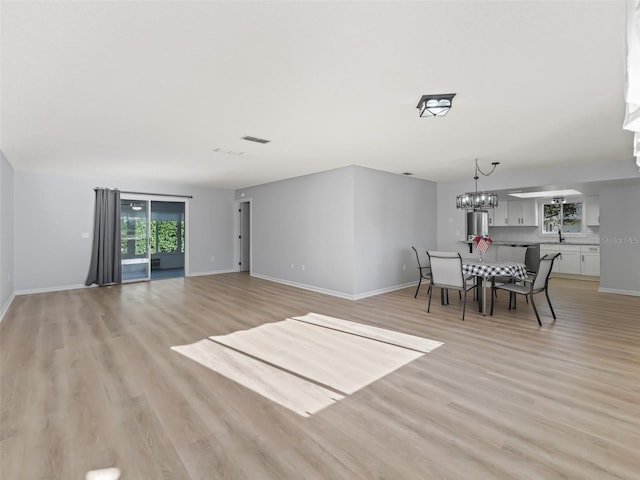 dining space with light hardwood / wood-style flooring, a chandelier, and sink