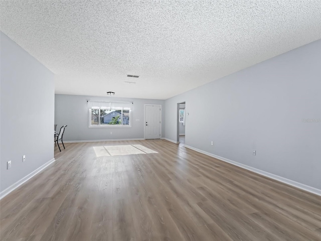 unfurnished living room with wood-type flooring and a textured ceiling