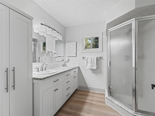 bathroom featuring vanity, hardwood / wood-style floors, a textured ceiling, and walk in shower