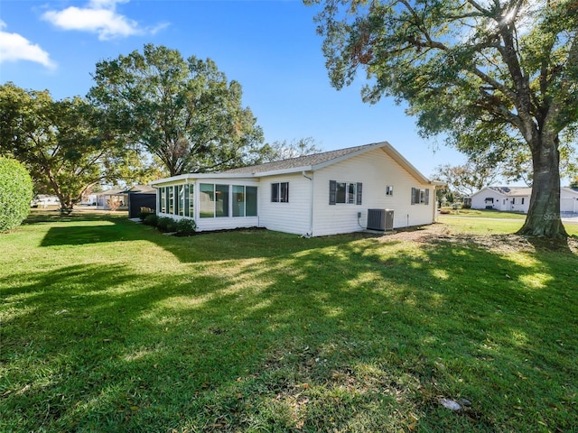 rear view of house featuring a sunroom, cooling unit, and a yard