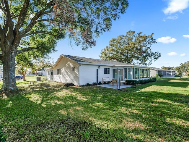 rear view of property featuring a sunroom, a patio area, and a lawn