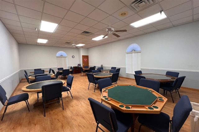 rec room with a paneled ceiling, ceiling fan, and light hardwood / wood-style flooring