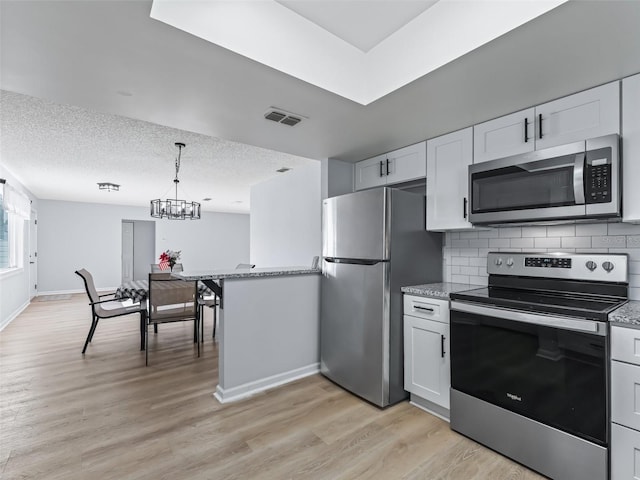 kitchen with backsplash, light hardwood / wood-style flooring, a textured ceiling, white cabinetry, and stainless steel appliances