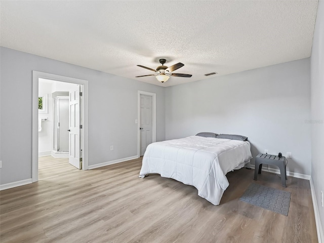 bedroom featuring ceiling fan, light hardwood / wood-style flooring, ensuite bathroom, and a textured ceiling