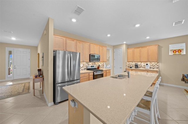 kitchen with a center island with sink, light brown cabinets, sink, and appliances with stainless steel finishes