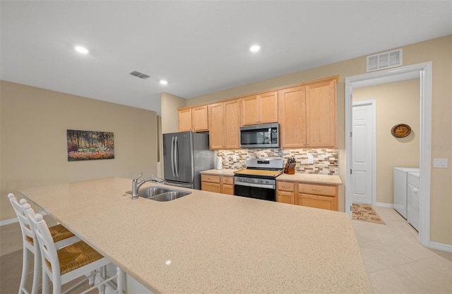 kitchen with separate washer and dryer, light brown cabinets, and stainless steel appliances